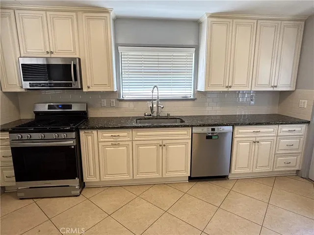 a kitchen with stainless steel appliances granite countertop a stove a sink and a microwave