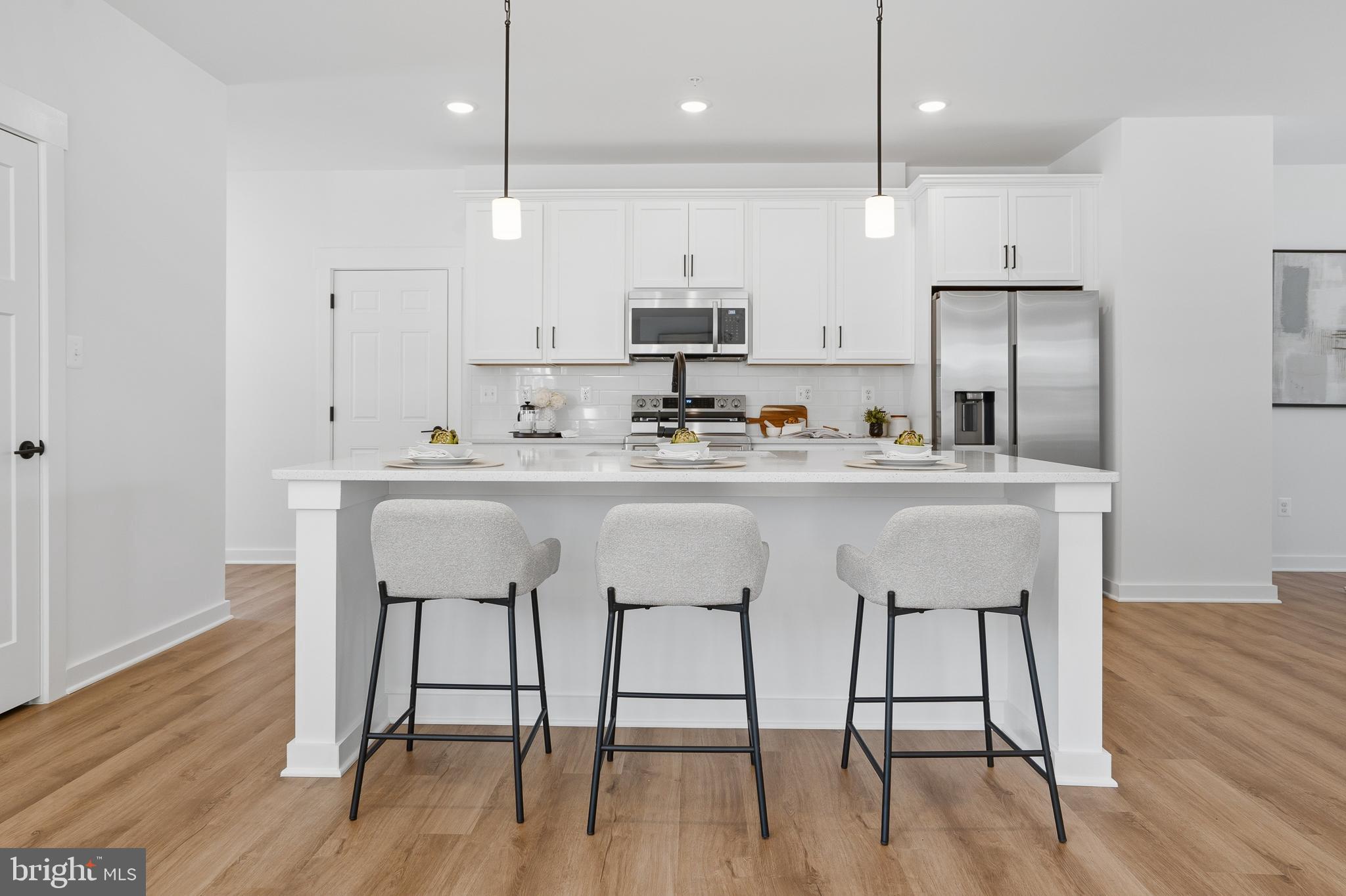 26 Walnut Street Middletown, MD 21769 - Photo 8 of 41 a kitchen with stainless steel appliances granite countertop a kitchen island a stove a refrigerator a sink a dining table and chairs with wooden floor