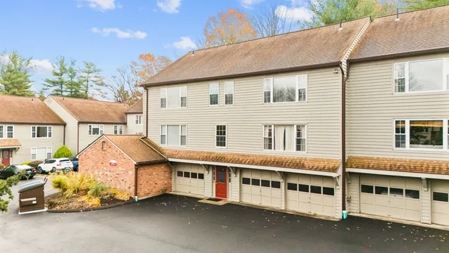 a view of a white house with large windows and a car park in front of it