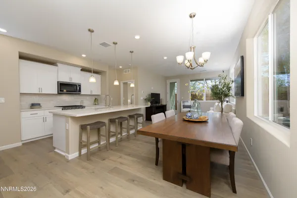 a open kitchen with stainless steel appliances granite countertop a stove top oven a sink dishwasher a dining table and chairs with wooden floor