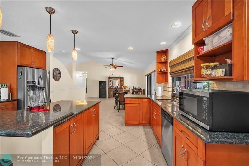 a large kitchen with stainless steel appliances kitchen island granite countertop a large counter top and a stove