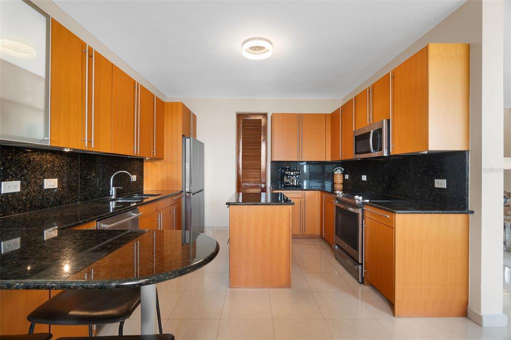 1 Palma Real Avenue, Unit 2 A6 Guaynabo, PR 00969 - Photo 15 of 49 a kitchen with stainless steel appliances granite countertop a stove a refrigerator a sink a stove with wooden cabinets and chairs