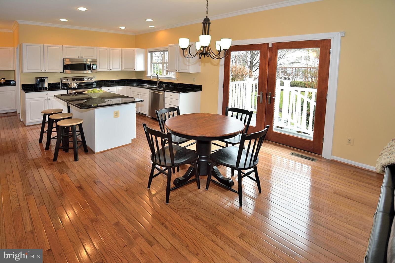 2303 Hurlingham Lane Reston, VA 20191 - Photo 3 of 30 a kitchen with stainless steel appliances granite countertop a stove a refrigerator a kitchen island a dining table and chairs with wooden floor