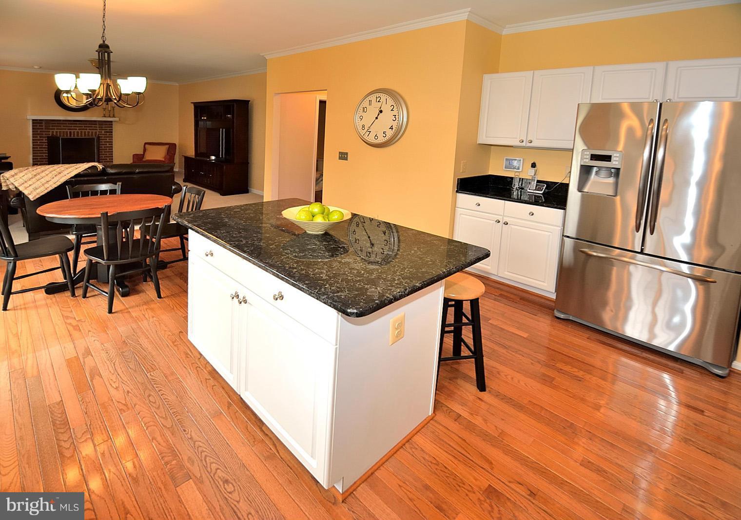 2303 Hurlingham Lane Reston, VA 20191 - Photo 5 of 30 a kitchen with stainless steel appliances granite countertop a refrigerator a stove a sink dishwasher and a dining table with wooden floor