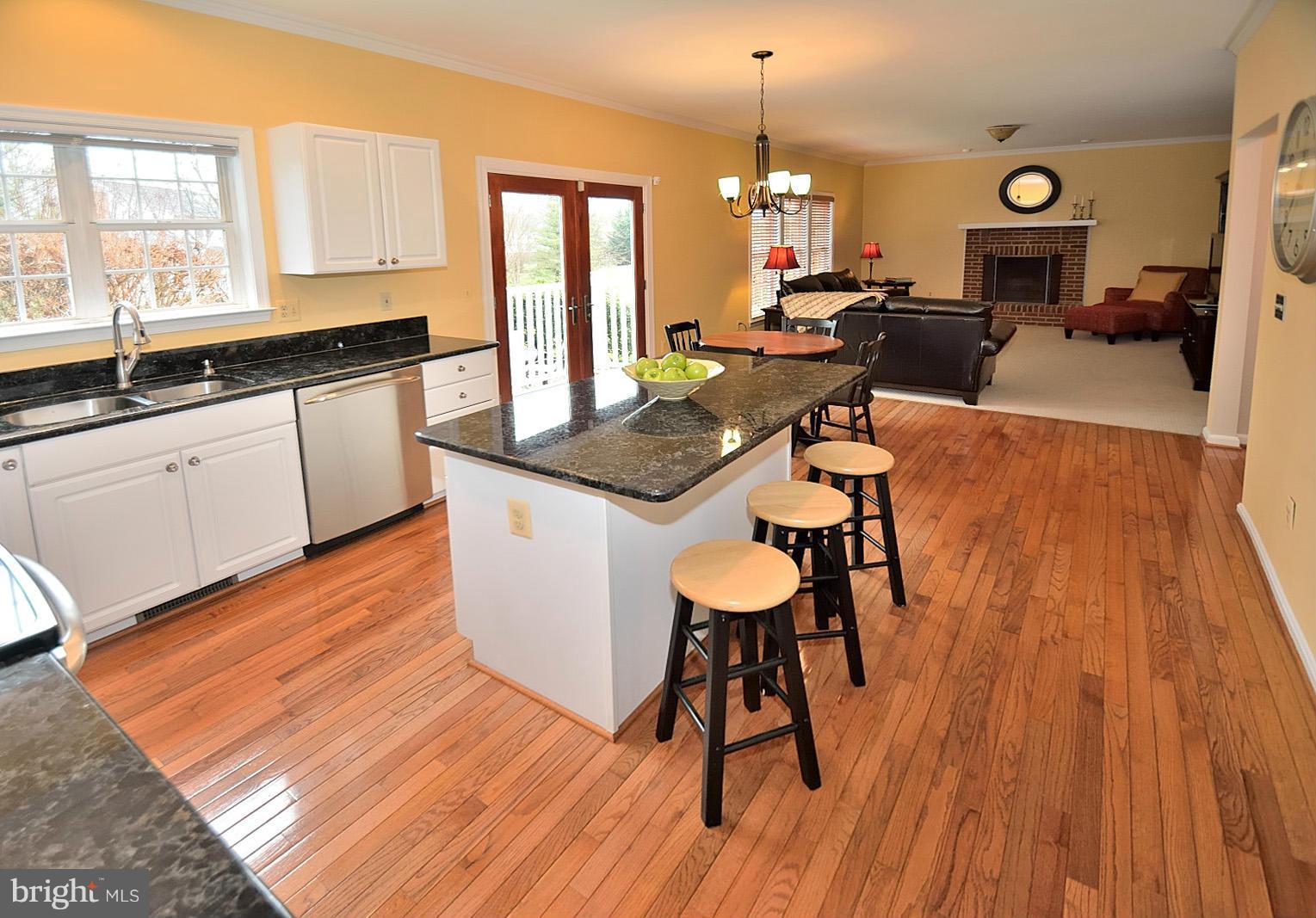 2303 Hurlingham Lane Reston, VA 20191 - Photo 6 of 30 a open kitchen with granite countertop a sink dishwasher a dining table and chairs with wooden floor