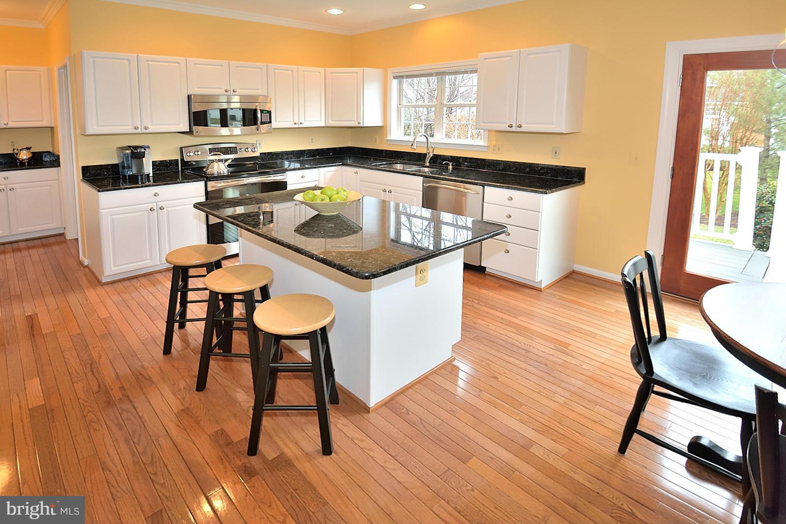 2303 Hurlingham Lane Reston, VA 20191 - Photo 7 of 30 a kitchen with stainless steel appliances granite countertop a table chairs stove a sink dishwasher and cabinets with wooden floor