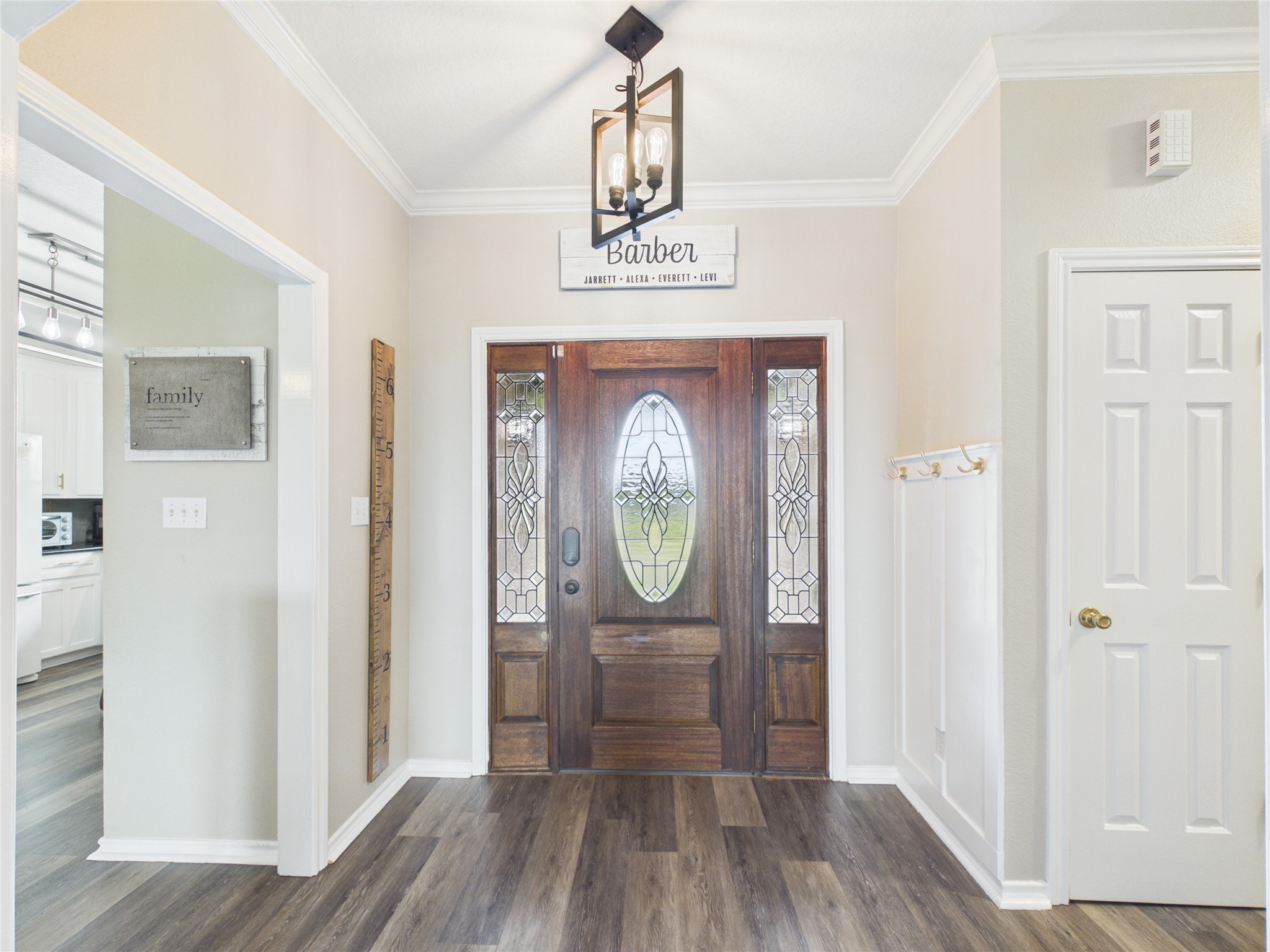 4610 Mustang Road Alvin, TX 77511 - Photo 8 of 50 View of front entry, coat closet, kitchen, dining room and sun/play room is to the left, family room is directly adjacent the entry way, hallway to the right leads to all bedrooms/bathrooms. Updated light fixtures throughout, updated floors, fresh paint, entry way accent wall with hooks for coats, purses, or backpacks. Abundant crown molding throughout this beautiful home.