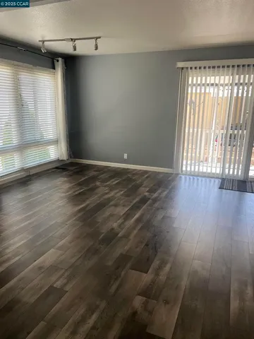 a view of an empty room with wooden floor and a window