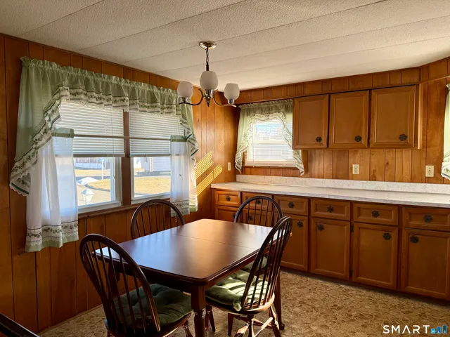 a dining room with stainless steel appliances granite countertop a sink a stove a dining table and chairs with wooden floor