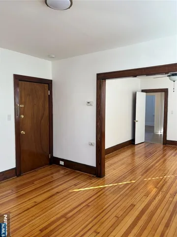 a view of an empty room with wooden floor and closet