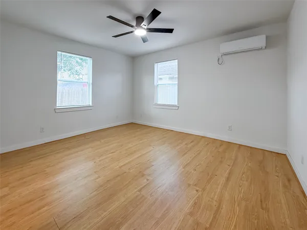 a view of an empty room with a window and wooden floor