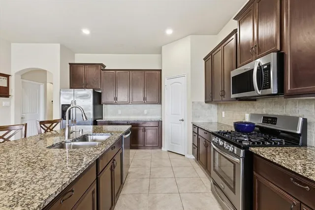 a kitchen with stainless steel appliances granite countertop a sink stove microwave and refrigerator