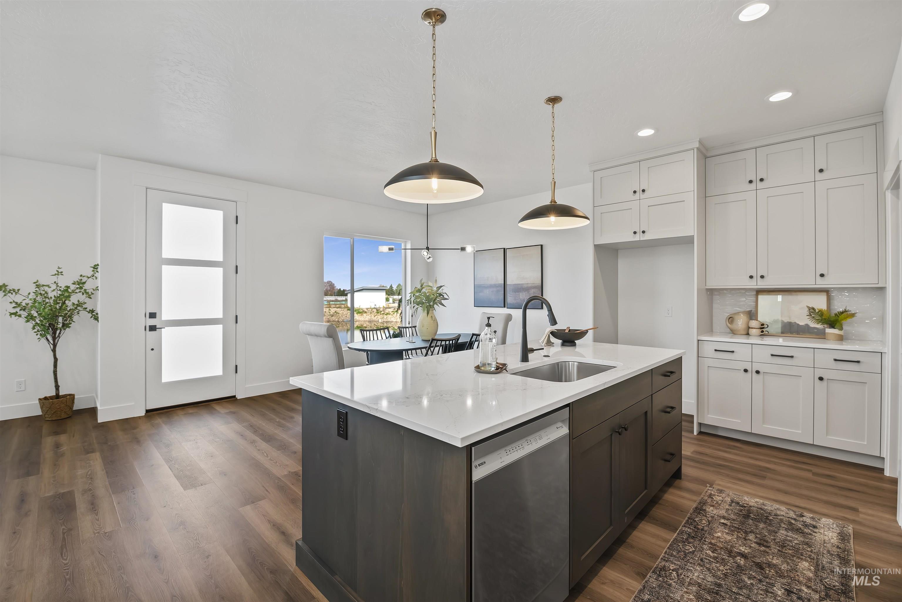749 South Calhoun Lane Star, ID 83669 - Photo 10 of 34 Kitchen featuring two tone cabinets, dishwasher, dark wood finished floors, decorative light fixtures, and light stone counters