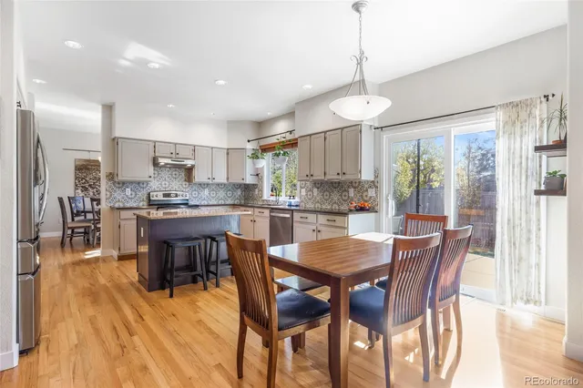 a dining area with stainless steel appliances kitchen island granite countertop a dining table chairs and granite counter tops