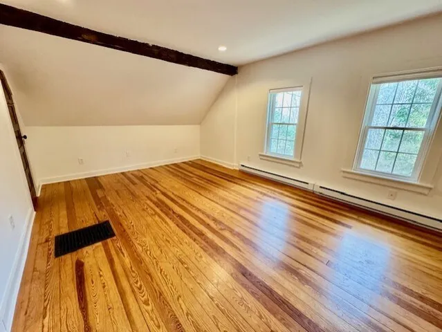 a view of empty room with wooden floor and windows