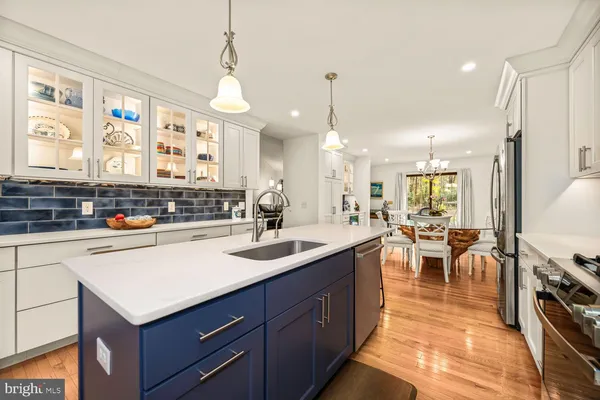 a kitchen with stainless steel appliances granite countertop a stove a sink a microwave a dining table and chairs with wooden floor