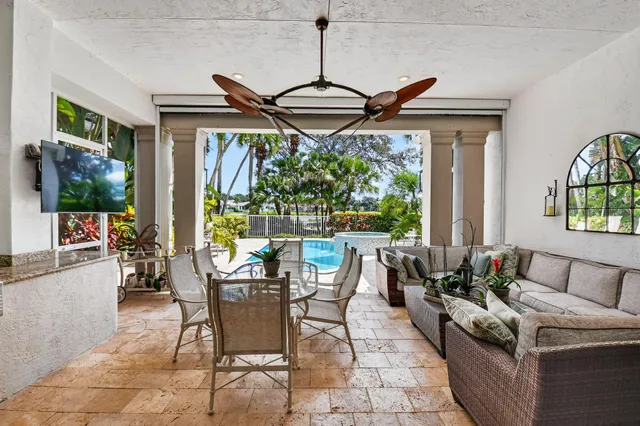 a view of a patio with dining table and chairs potted plants and palm trees