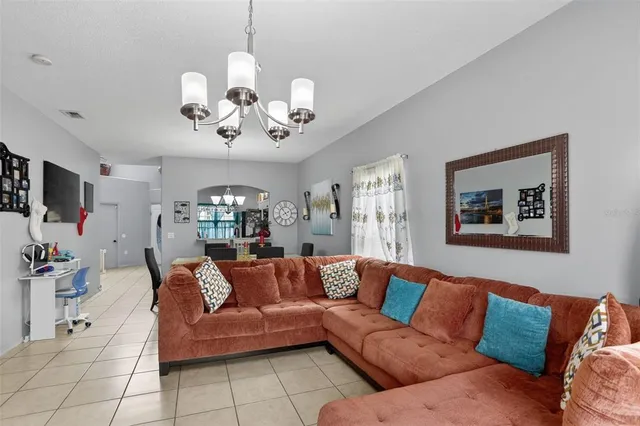 a living room with furniture a chandelier and a flat screen tv