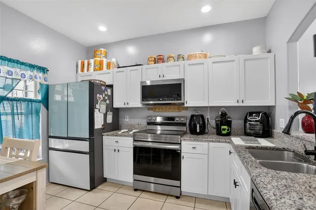 a kitchen with granite countertop a sink stove and refrigerator