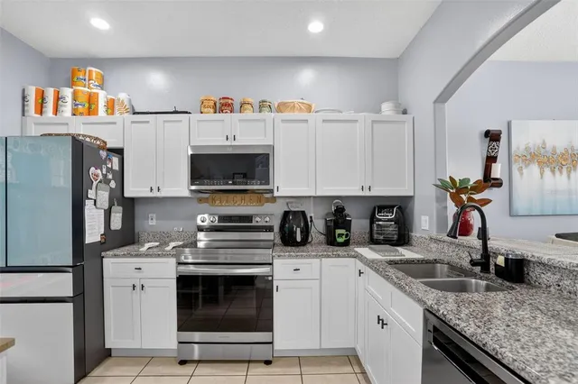 a kitchen with granite countertop a sink stainless steel appliances and white cabinets