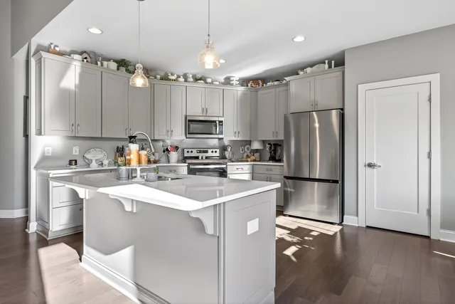 a kitchen with kitchen island white cabinets a sink a refrigerator and a stove