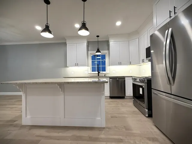 a kitchen with kitchen island a counter top space stainless steel appliances and cabinets