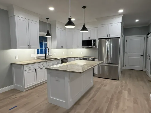 a kitchen with kitchen island a sink stainless steel appliances and refrigerator