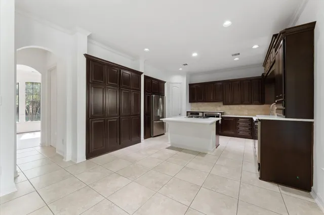 a large kitchen with stainless steel appliances kitchen island granite countertop a refrigerator and a sink