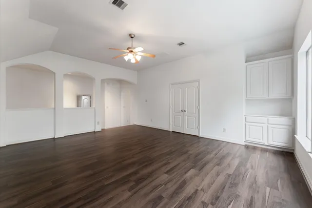 a view of an empty room with a window and wooden floor