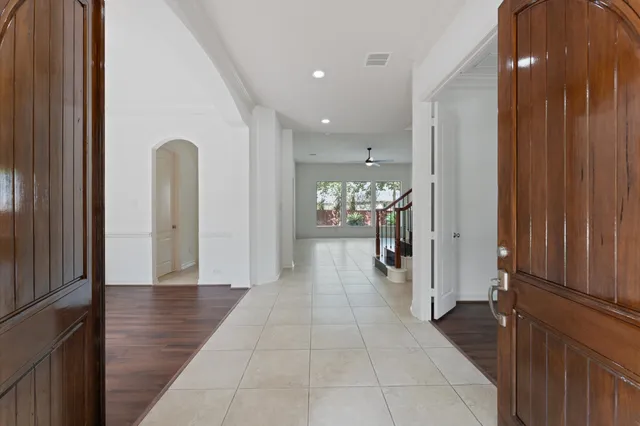 a view of a hallway with wooden floor a chandelier and a bathroom