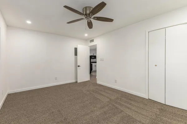 an empty room with closet and a ceiling fan