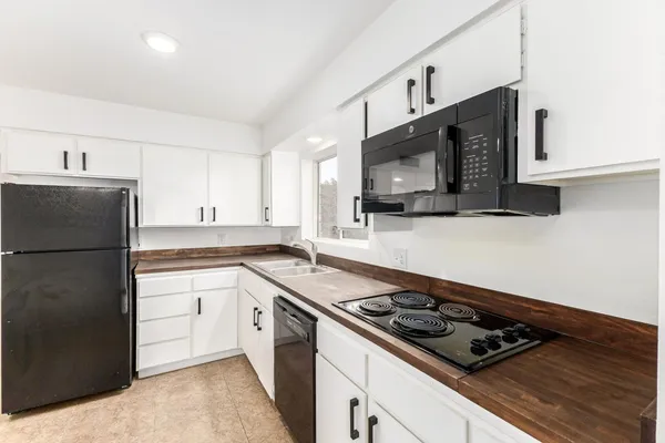 a kitchen with stainless steel appliances a sink a stove a microwave a refrigerator a cabinets and wooden floor