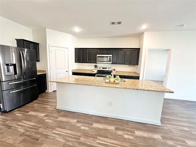 a kitchen with stainless steel appliances granite countertop a stove top oven a sink with wooden floors