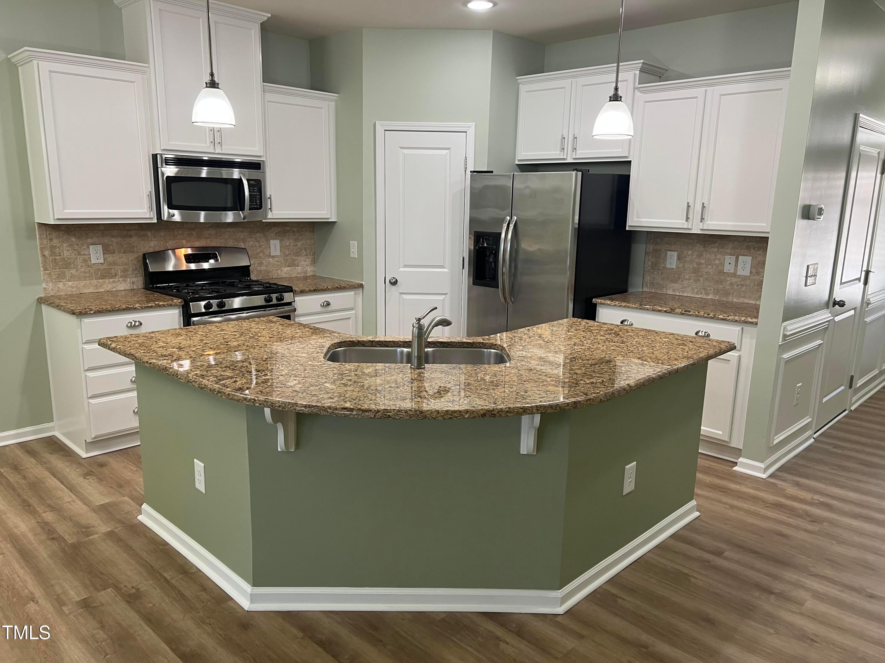 714 Treviso Lane Apex, NC 27502 - Photo 11 of 27 a kitchen with granite countertop a refrigerator a stove and a sink