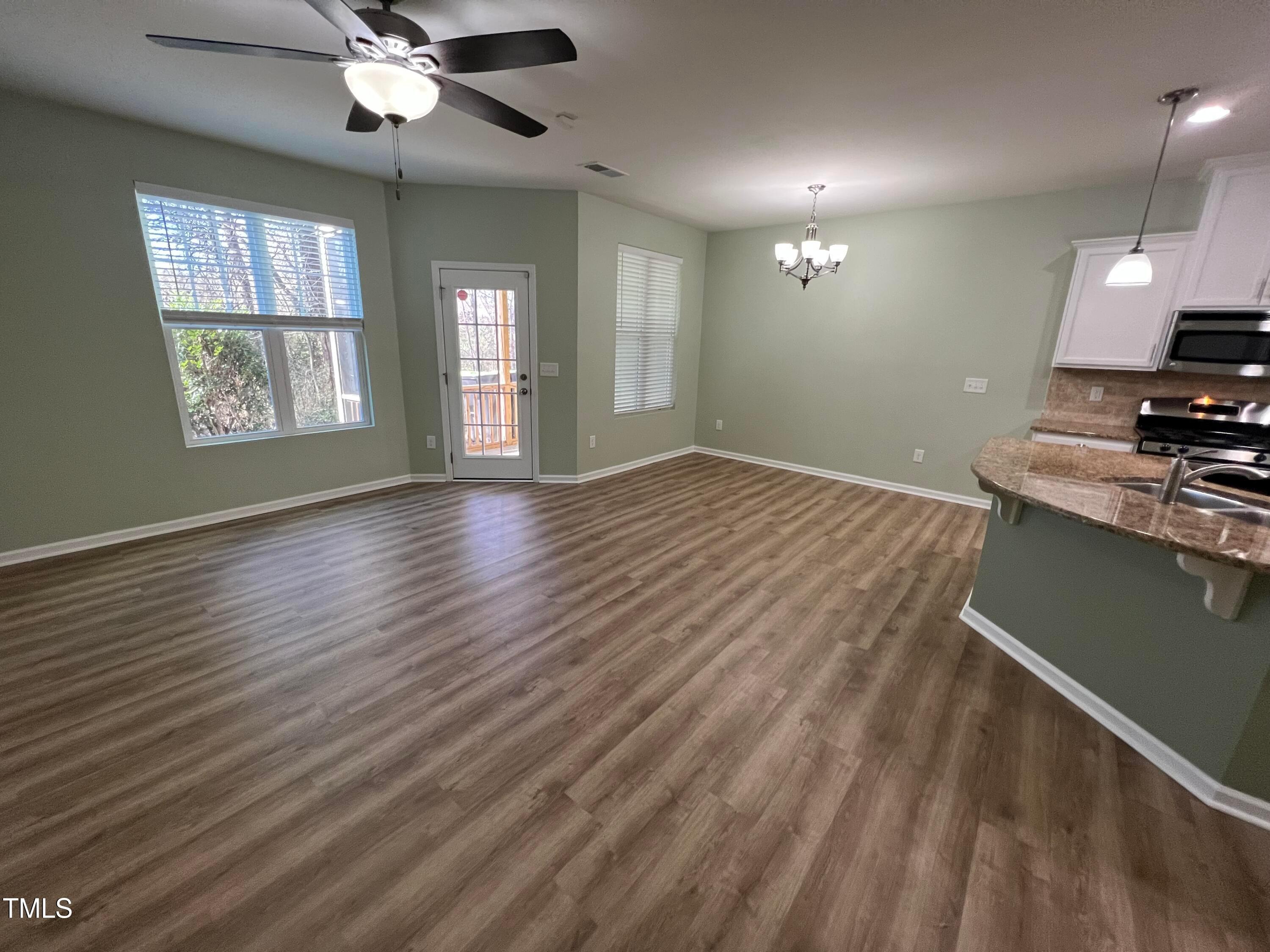 714 Treviso Lane Apex, NC 27502 - Photo 12 of 27 an empty room with wooden floor chandelier fan and windows