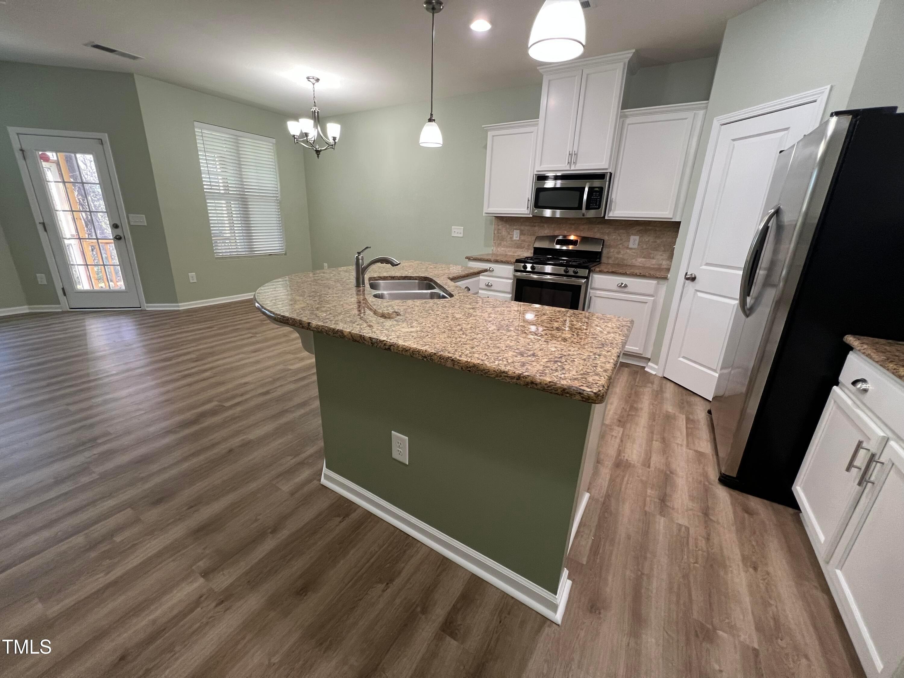 714 Treviso Lane Apex, NC 27502 - Photo 6 of 27 a kitchen with kitchen island granite countertop a sink stove and refrigerator