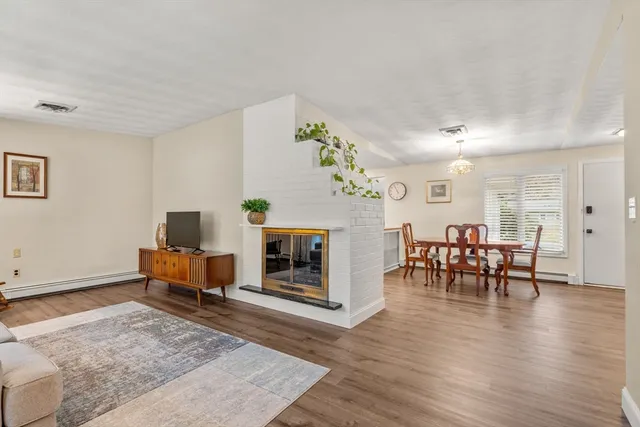 a living room with furniture and a dining table with wooden floor