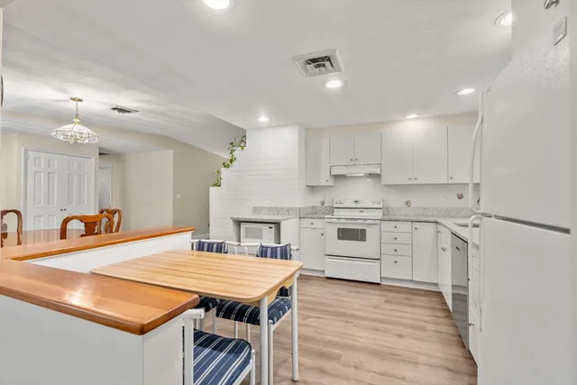 a kitchen with stainless steel appliances kitchen island granite countertop a sink a stove a refrigerator and white cabinets