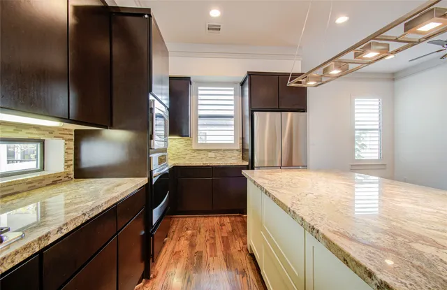 a large kitchen with a large counter top stainless steel appliances and cabinets