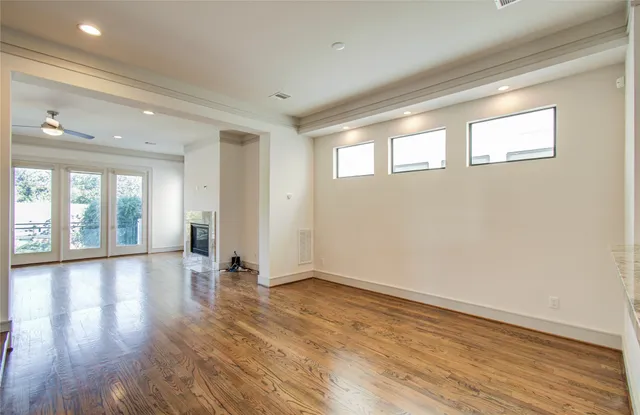 a view of empty room with wooden floor and kitchen