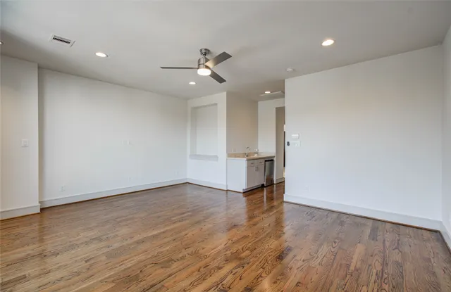 a view of an empty room with wooden floor and closet