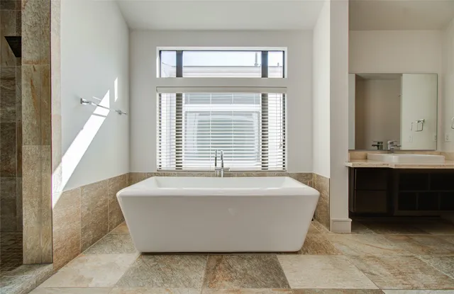 a spacious bathroom with a bathtub sink and mirror