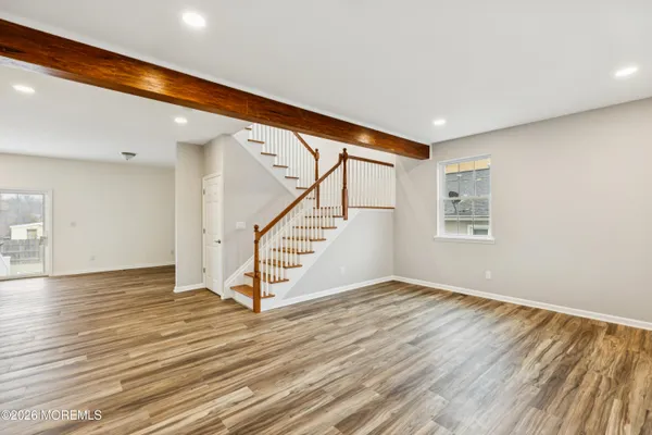 a view of an empty room with wooden floor and stairs