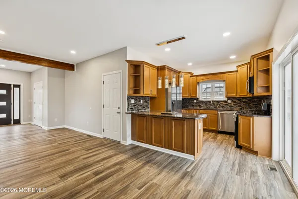 a kitchen with stainless steel appliances kitchen island granite countertop wooden floors and wide window