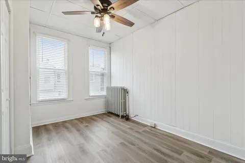 an empty room with a window and ceiling fan