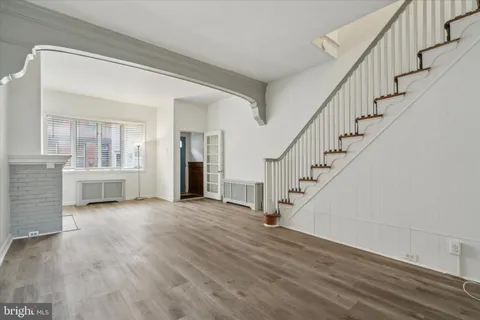 a view of an empty room with wooden floor and stairs