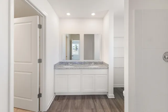 a bathroom with a granite countertop sink a mirror and a shower