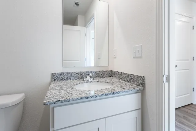 a bathroom with a granite countertop sink and a toilet