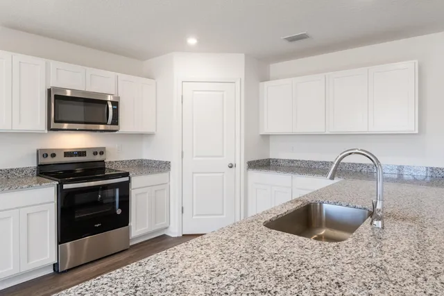 a kitchen with stainless steel appliances granite countertop a sink a stove and microwave