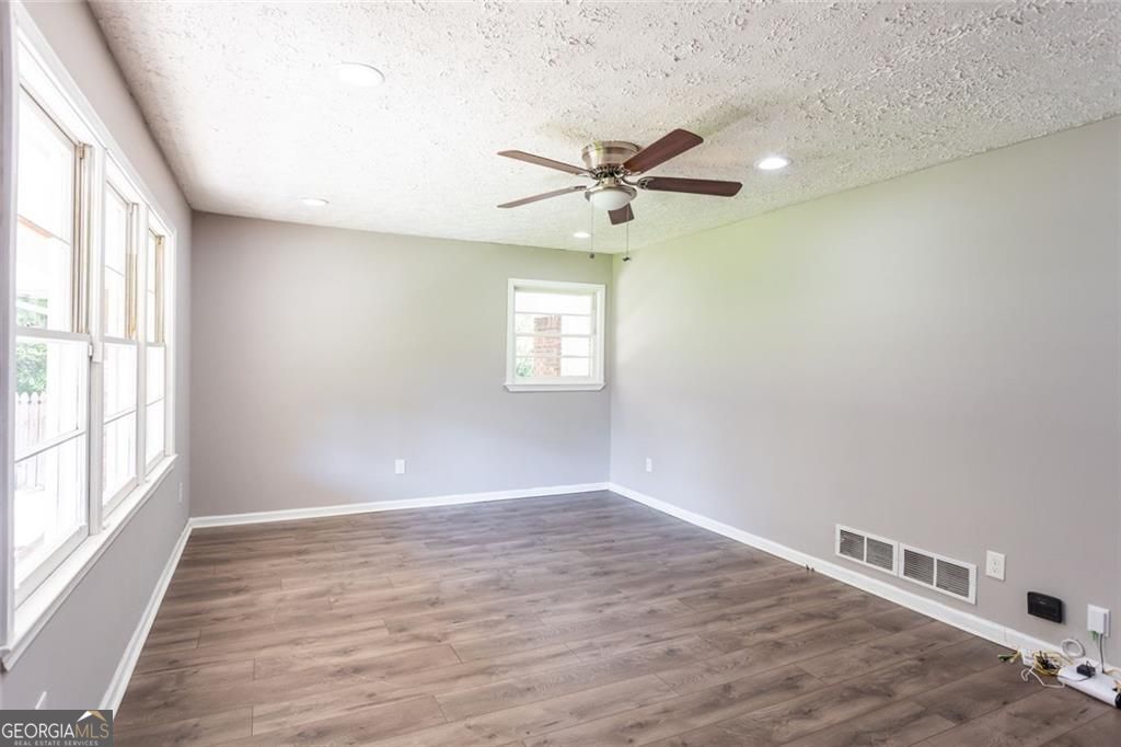 908 East Marable Street Monroe, GA 30656 - Photo 12 of 26 an empty room with wooden floor fan and windows